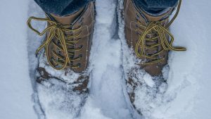 A Person in Brown Leather Shoes Standing on a Snow Covered Ground